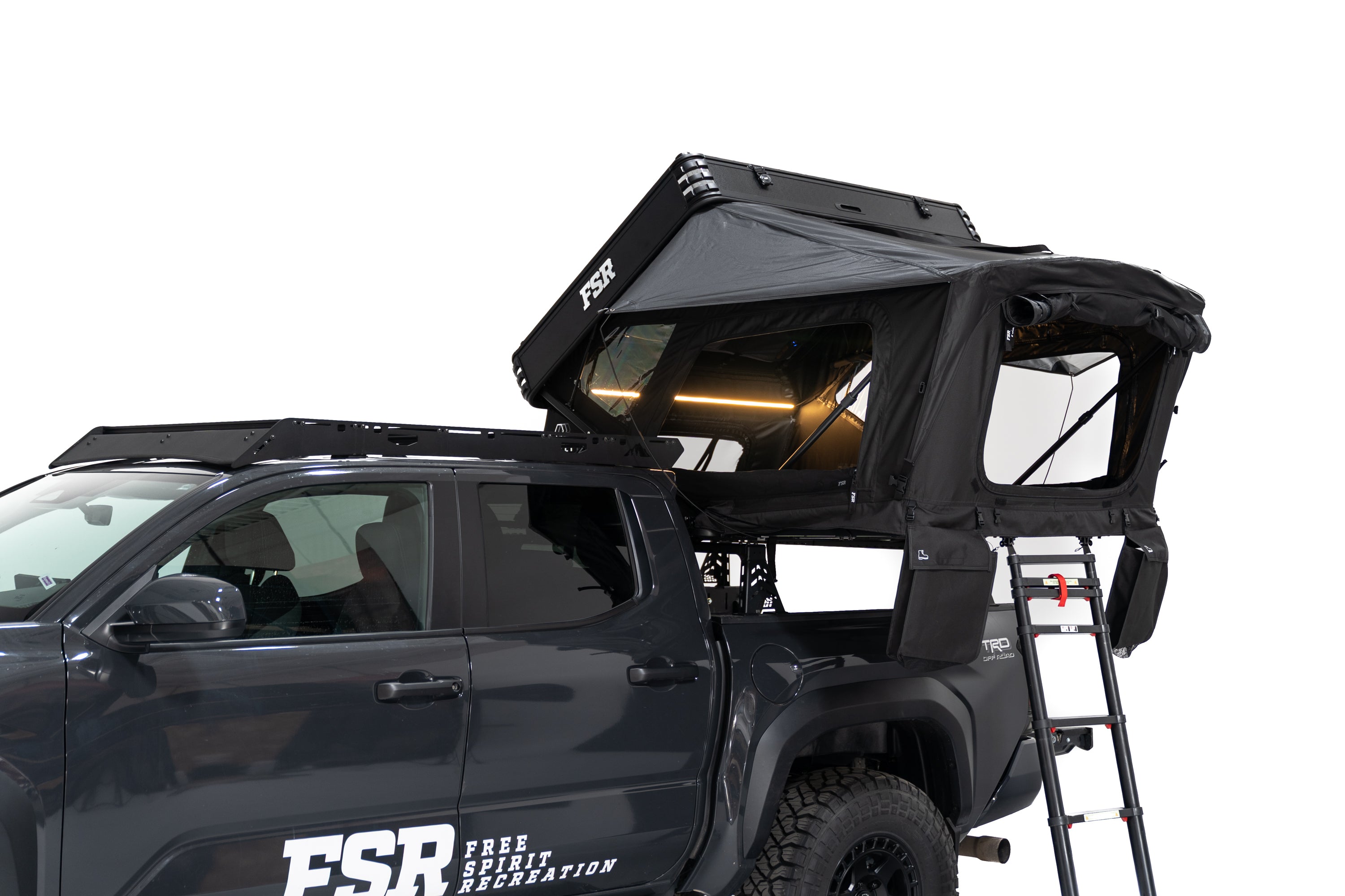 Exterior Photo of Kali hardshell rooftop tent by FSR - Deployed on the truck bed of a 4th gen Toyota Tacoma with the interior light on and the windows open.