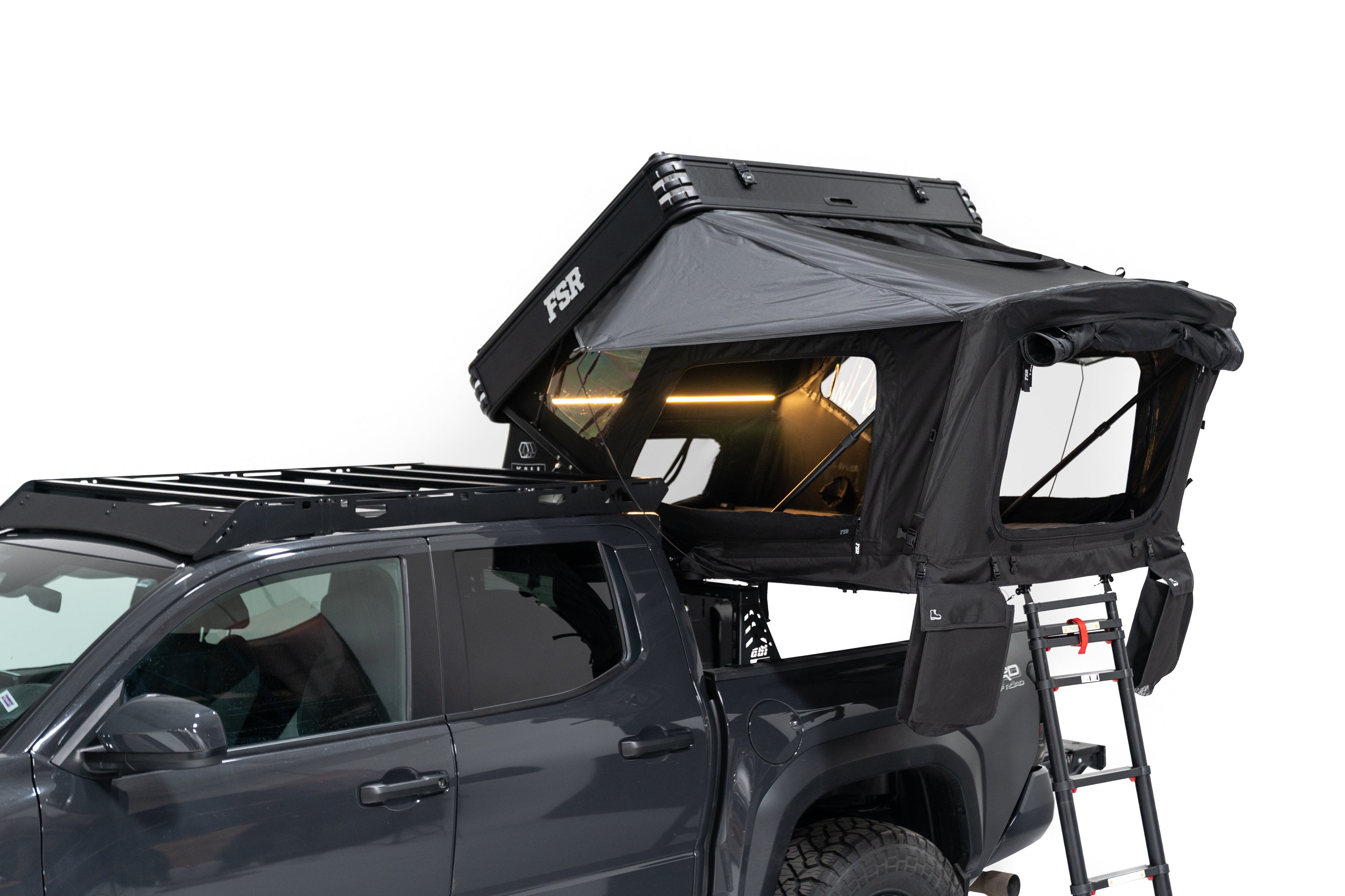 A different angle Exterior Photo of Kali hardshell rooftop tent by FSR - Deployed on the truck bed of a 4th gen Toyota Tacoma with lights on and windows open.