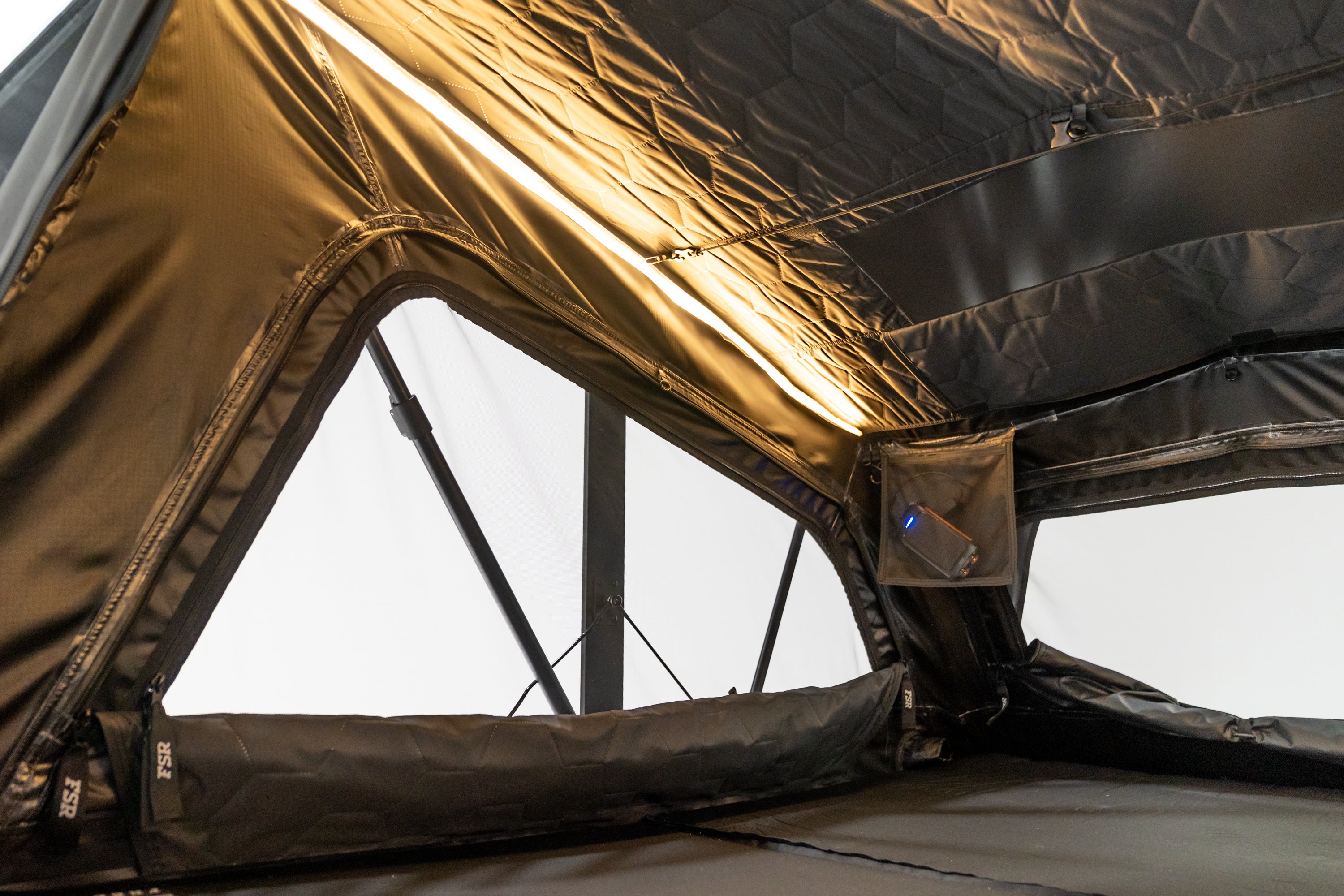 Interior Close up photo of the Nova King rooftop tent with the tent windows open and lights on.