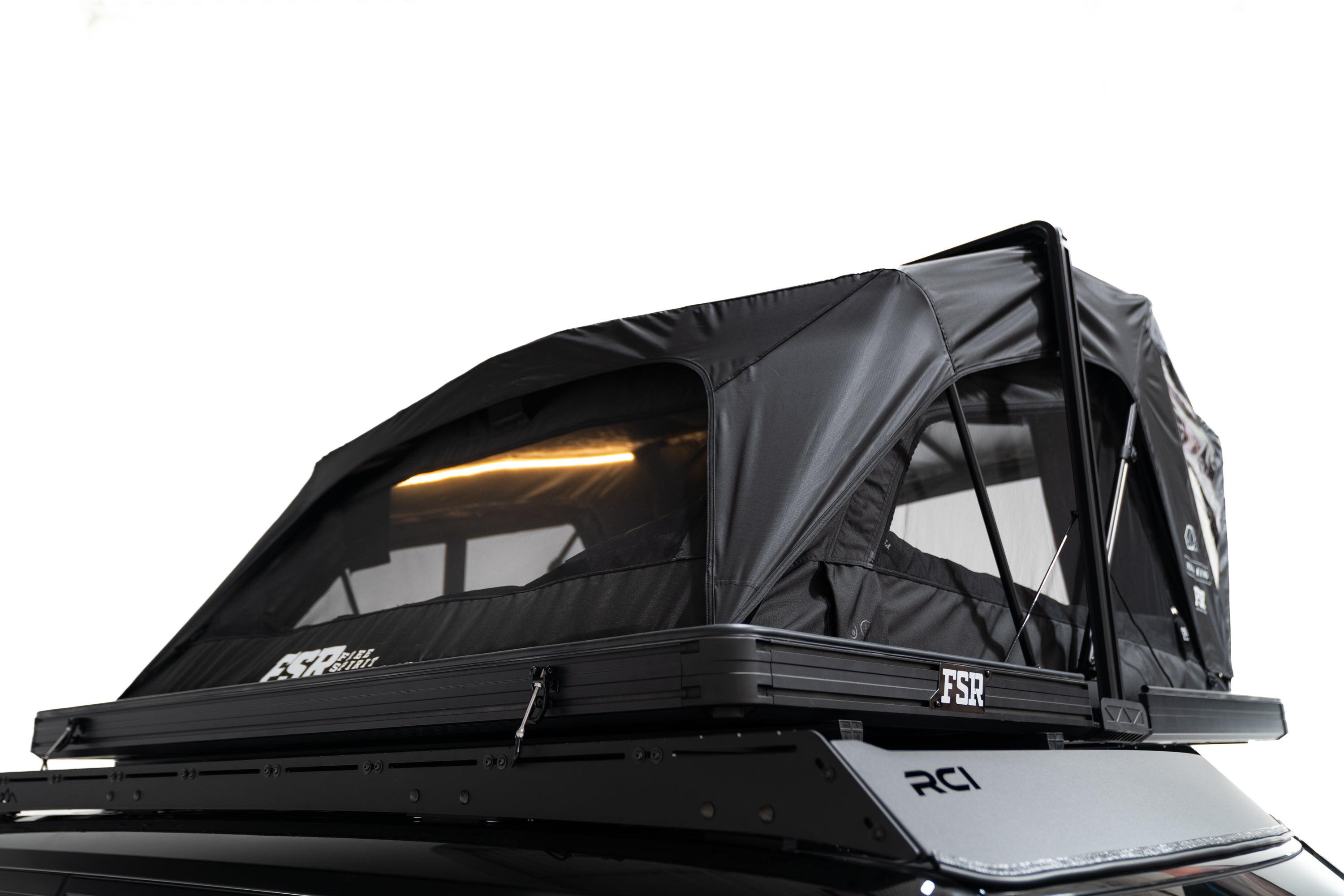 Reear angle Close up Exterior photo of the Nova King rooftop tent mounted on a white Toyota land cruiser with the tent windows open and lights on.