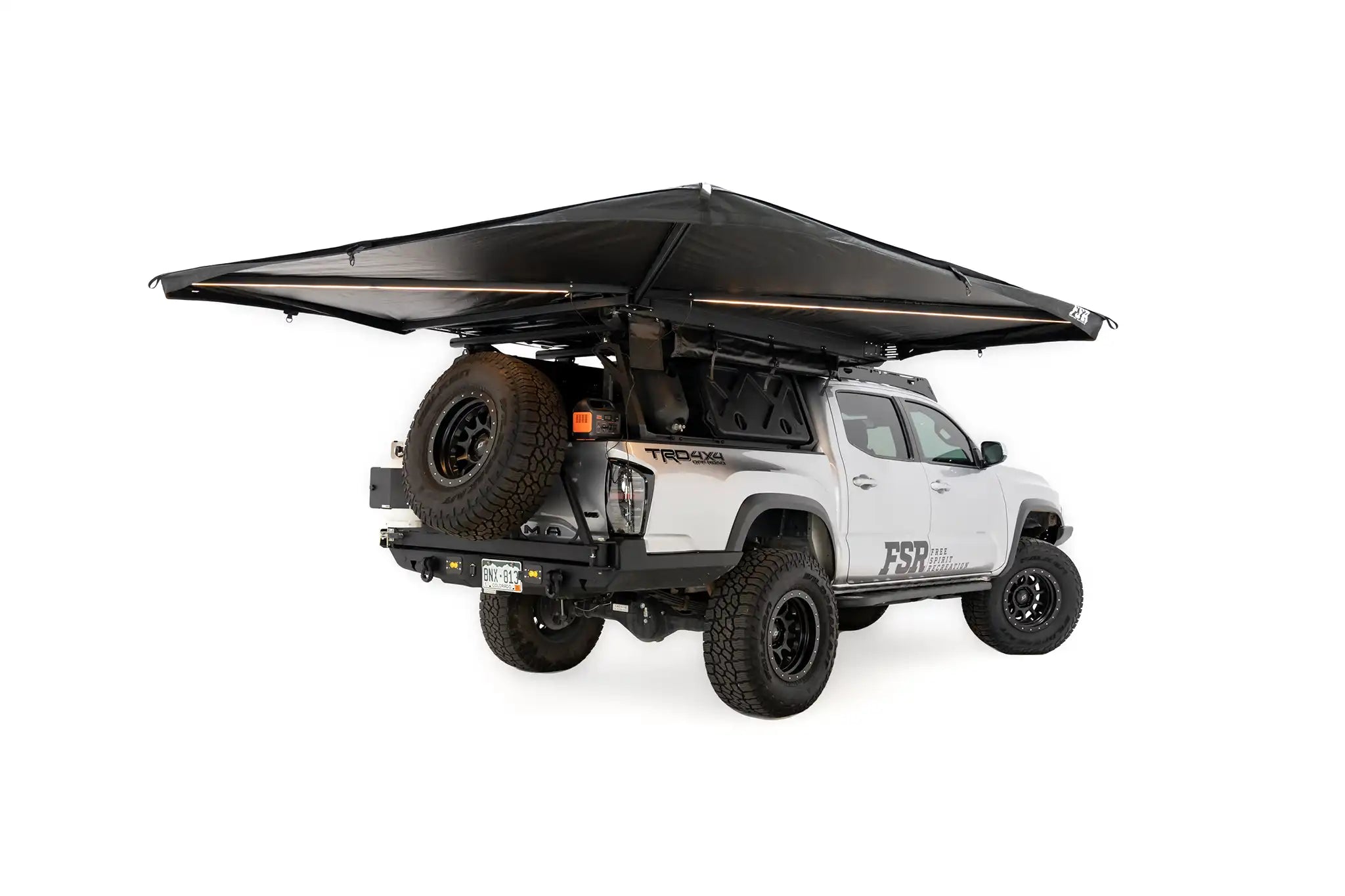 Photo of deployed FSR 270 Awning by Freespirit Recreation with integrated lighting illuminated, installed on a 4WD Toyota Tacoma overland truck build