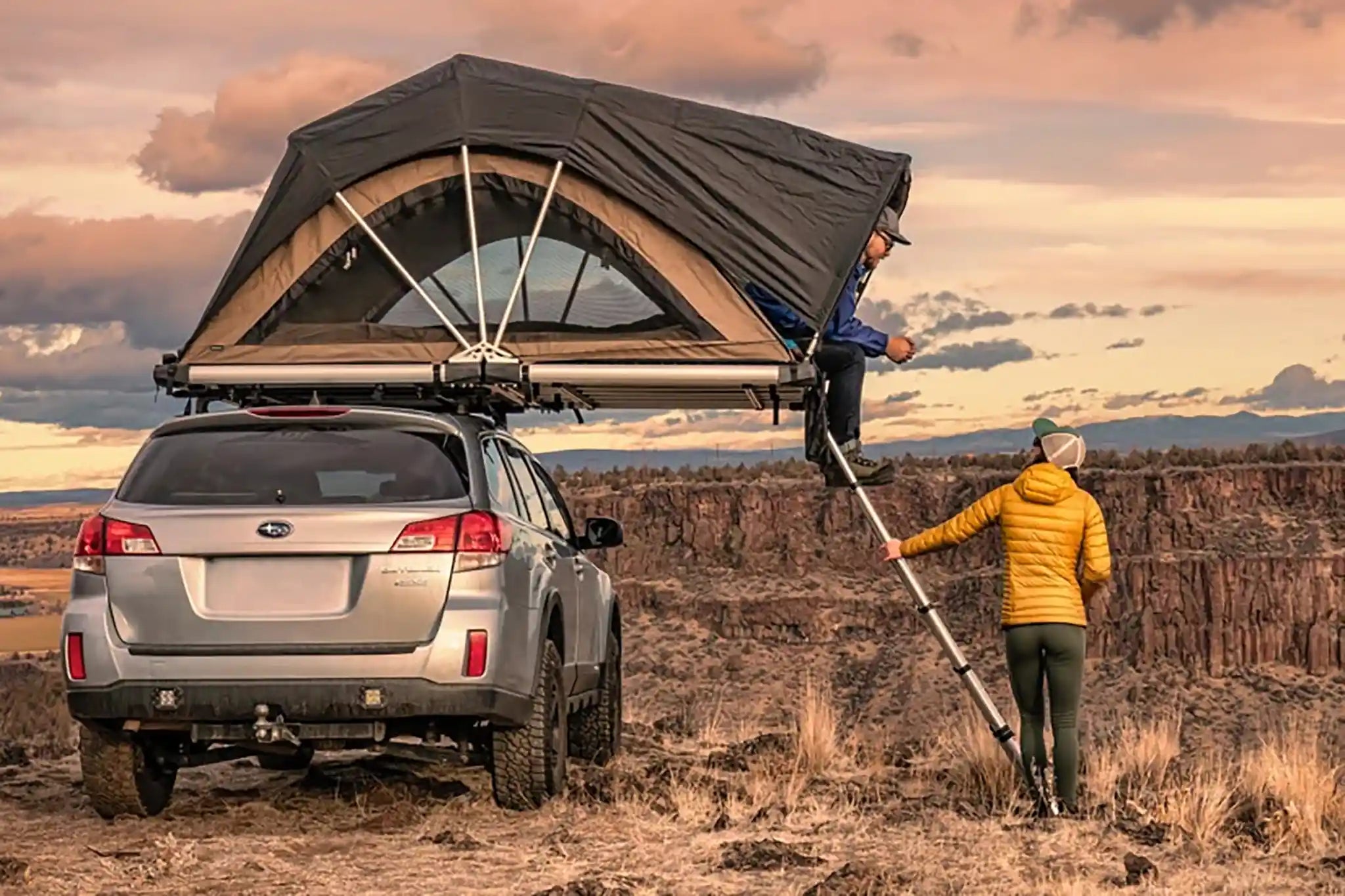 Two FSR affiliate partners setting up a rooftop tent on a car in a desert landscape.