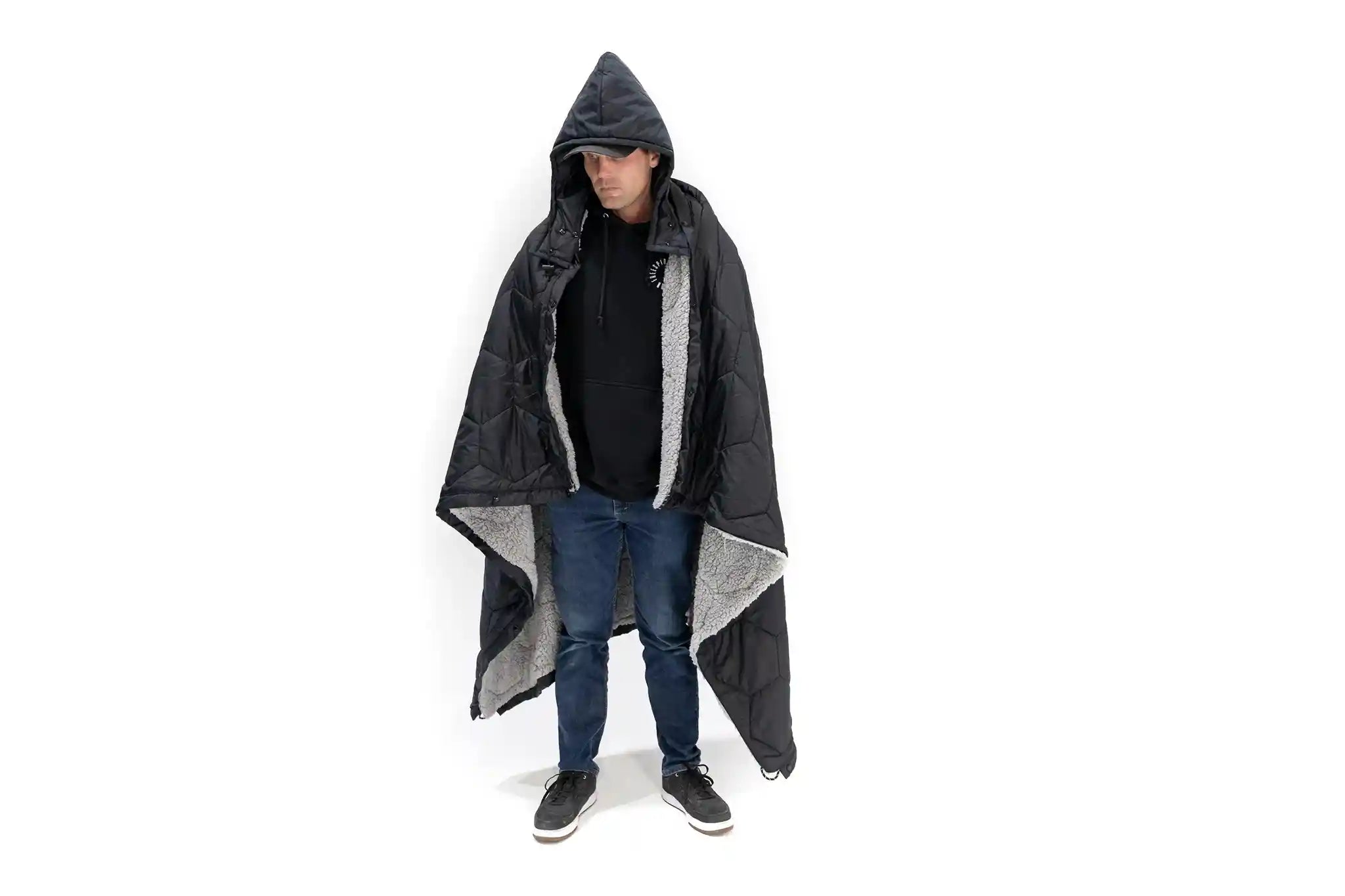 Man wearing the FSR Anywhere Camping Poncho Blanket with the built in poncho hood up.