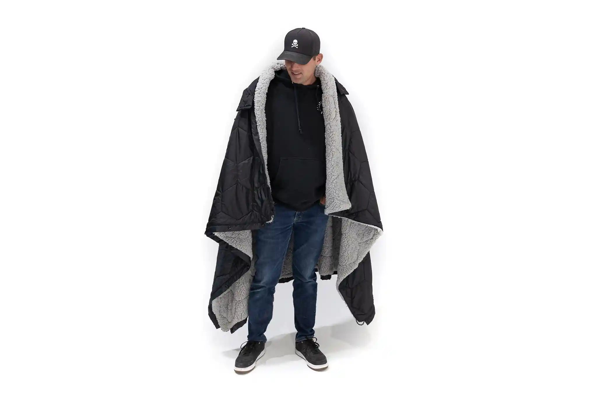 Man wearing the FSR Anywhere Camping Poncho Blanket, showing the gray sherpa lined interior and weather resistent black fabric shell