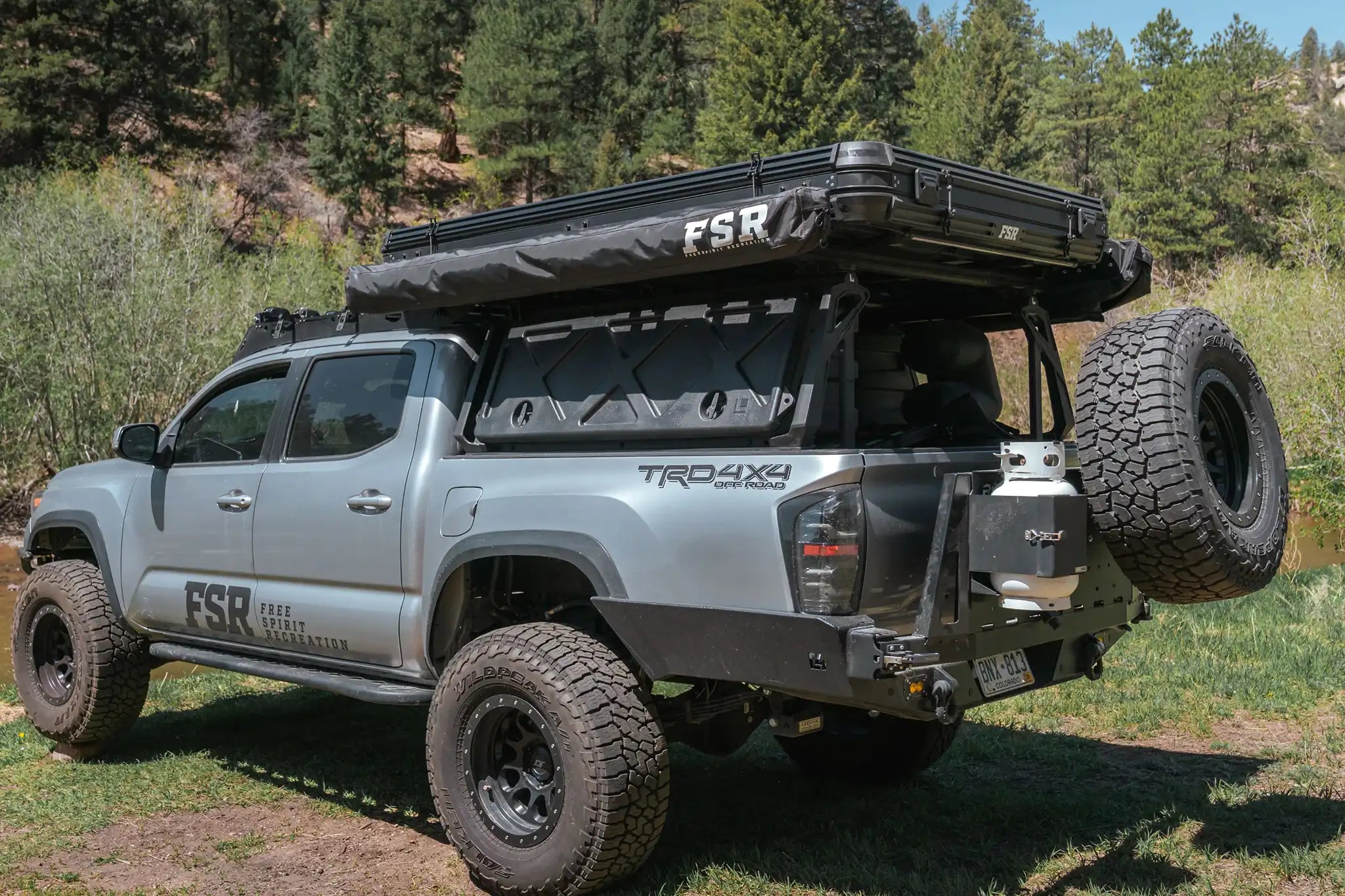 Image of the FSR Double Shower Awning & Privacy Tent closed and stored on a Toyota Tacoma overland truck parked off road at a campsite