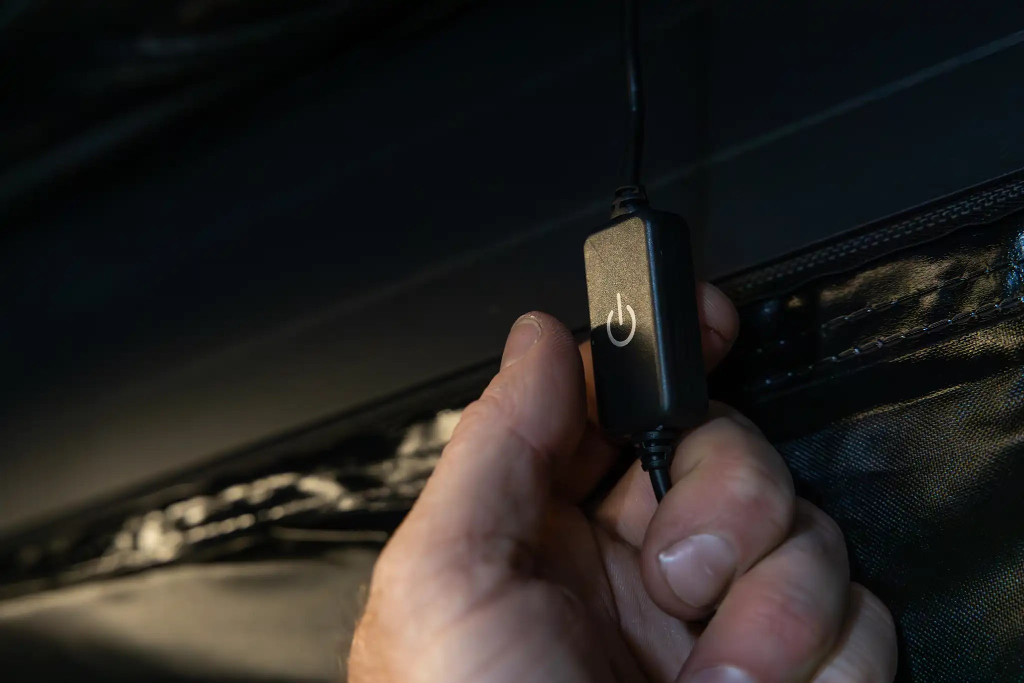 Close up photo of a person's hand using the FSR Double Shower Awning & Privacy Tent interior dimmable LED light switch.