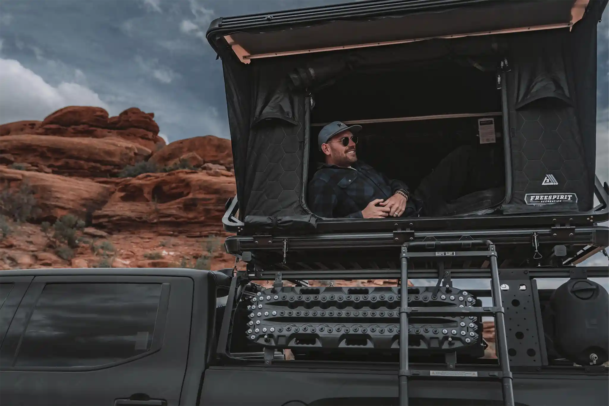 One of Free Spirit Recreation's rooftop tent fitment and installation experts relacing in an FSR Evo roof top tent mounted to their truck bed rack while camping in the desert
