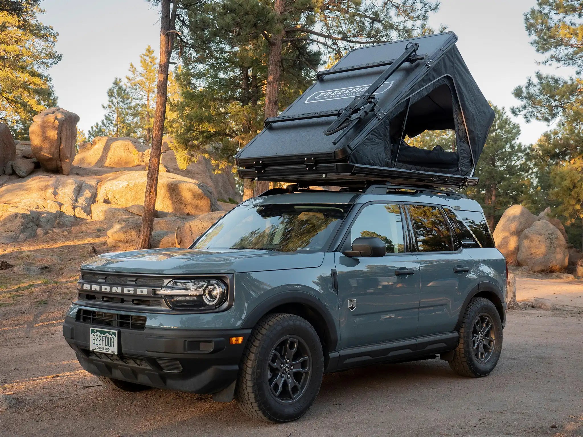 Ford Bronco with a Pair of FSR Crossbars installed on a Free Spirit Recreation hard shell roof top tent with a bike mount installed for carrying a mountain bike on top of the RTT while camping