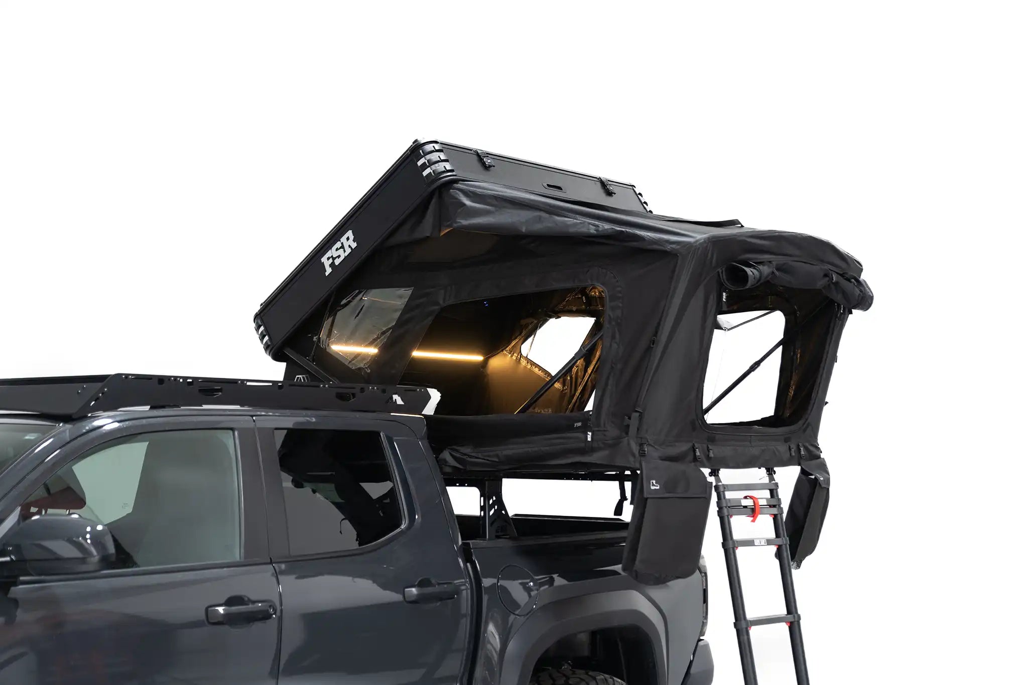 Close up exterior photo of FSR Kali hardshell rooftop tent deployed with dimmable lights on and windows open.