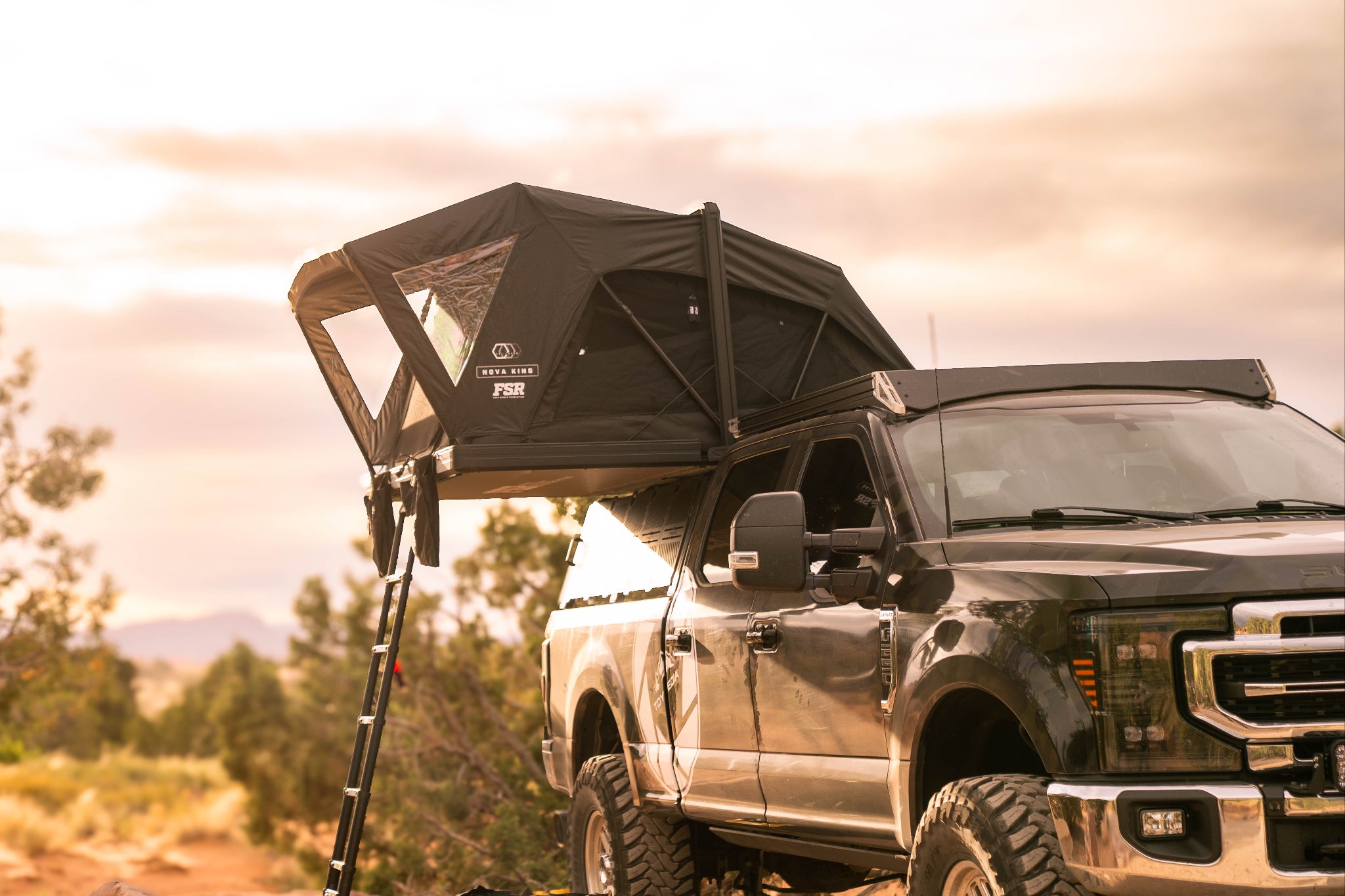 Black truck with a Nova King rooftop tent in a natural setting