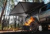 Freespirit Recreation 270 Awning installed on a Toyota Tacoma deployed while camping in a forested setting with a propane firepit visible in the foreground