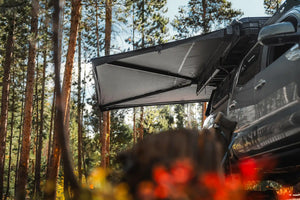 FSR 270 overland awning installed on a gray Toyota Tacoma deployed while camping in a forested campsite