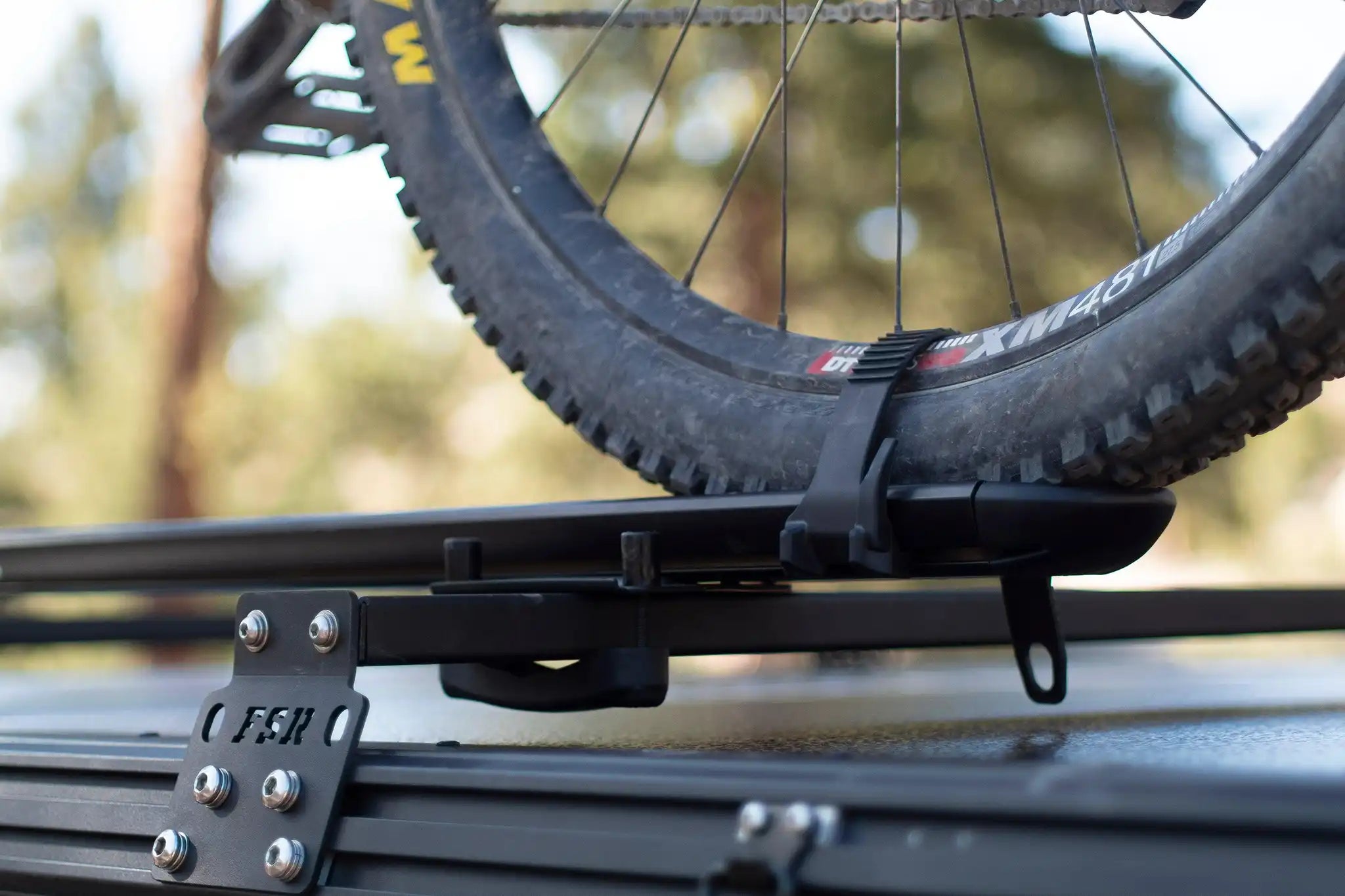 Close up of a bike mount installed on FSR Hardshell Series Crossbars mounted on a Free Spirit Recreation hard shell rooftop tent with a bike mount secured.