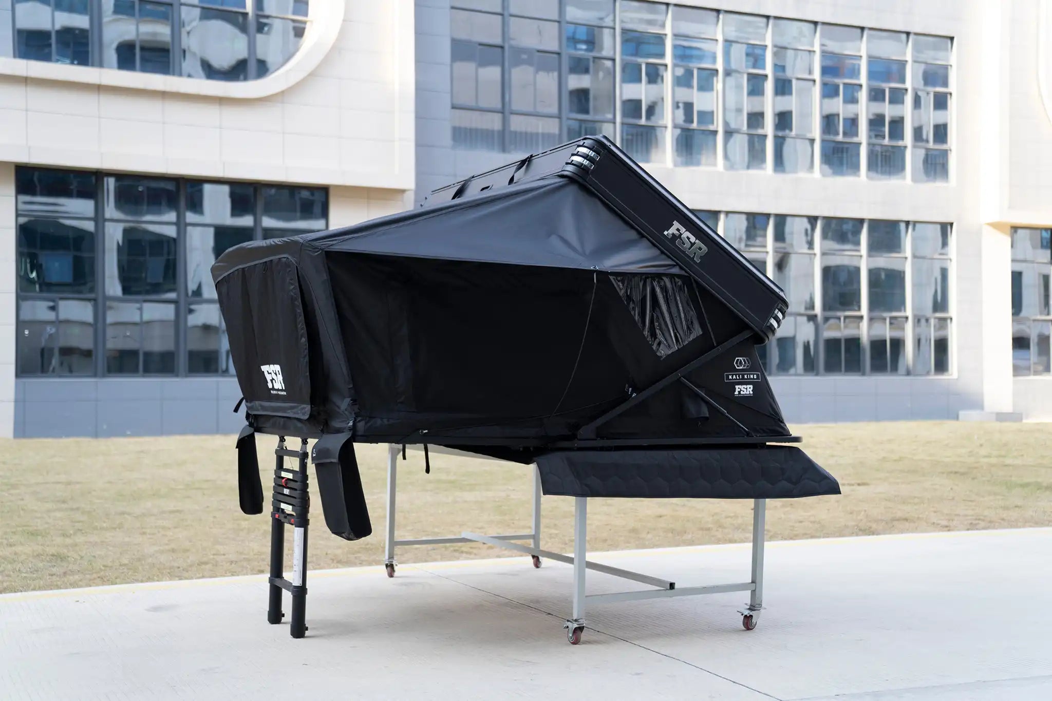 Side-facing image of the FSR Kali King hardshell roof top tent from Freespirit Recreation fully deployed with entry door and windows cloased and ladder collapsed.