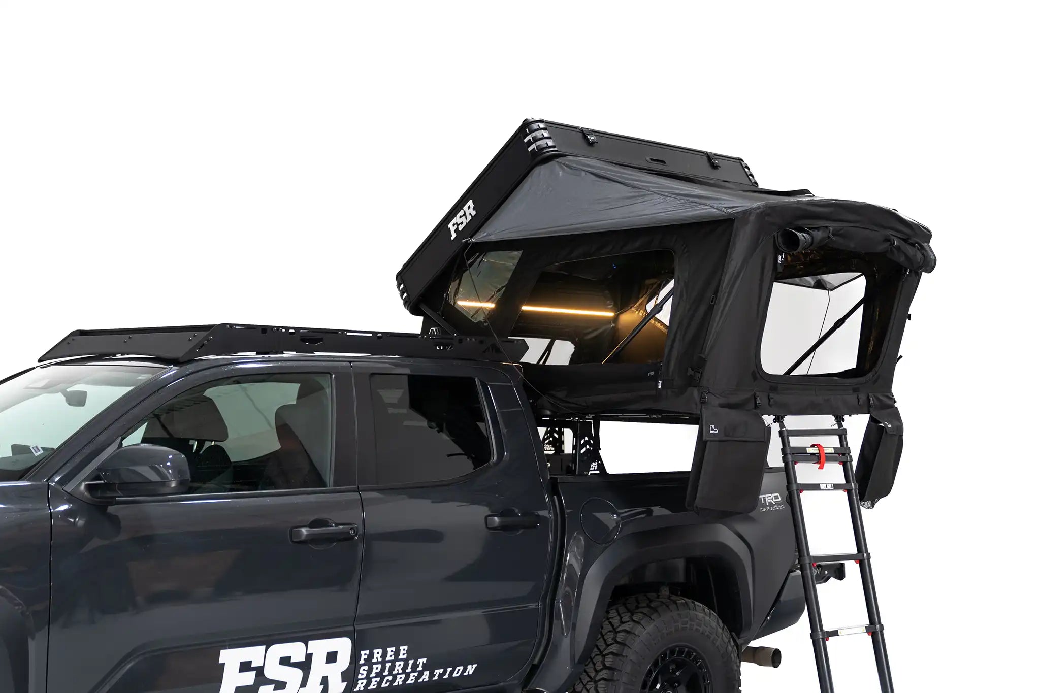 FSR Kali hardshell rooftop tent installed on a Toyota Tacoma with lights on and ladder attached.