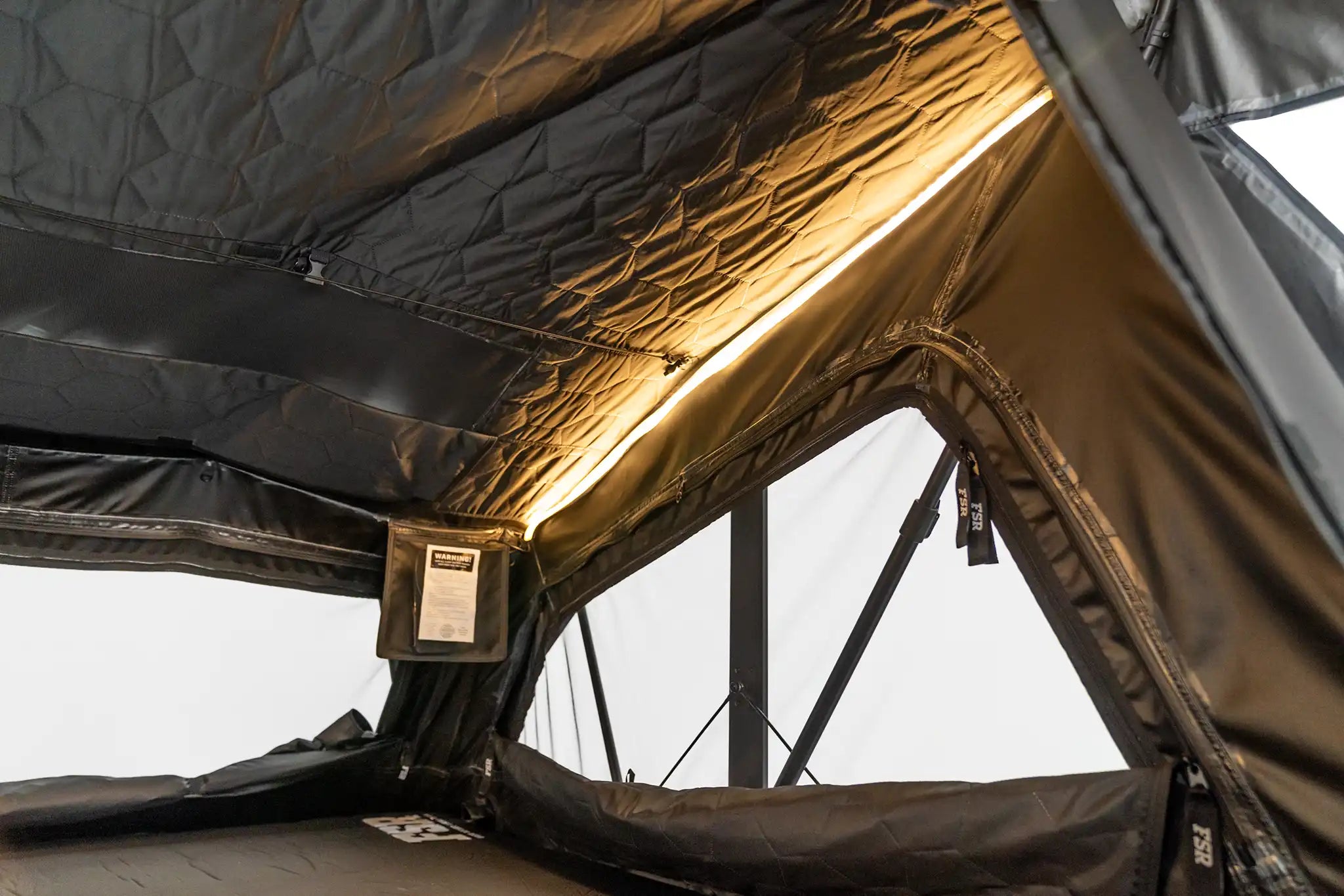 Righthand interior photo of the Nova King rooftop tent with the tent windows open and LED lights on.
