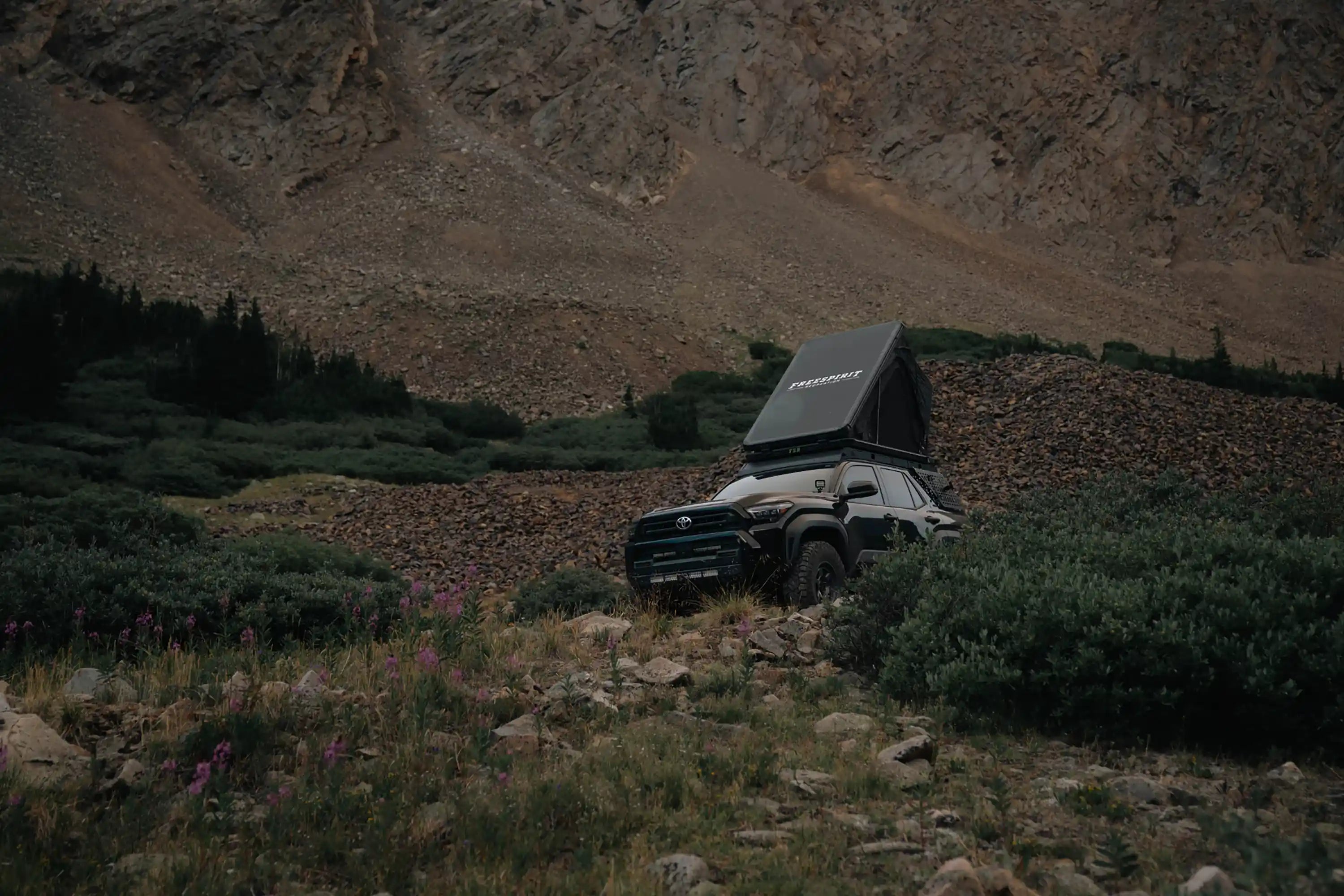 Toyota 4Runner with an FSR roof top tent installed and setup at a mountainous campsite at dusk with spring flowers in the foreground