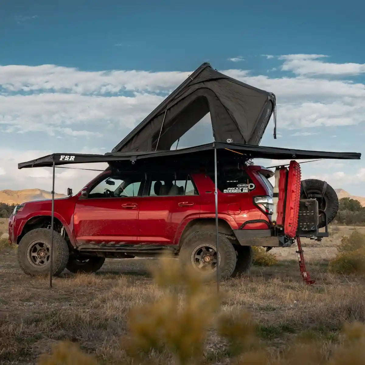 Red Toyota 4Runner with an FSR rooftop tent and Freespirit Recreation 180 degree awning deployed while camping in a desert landscape