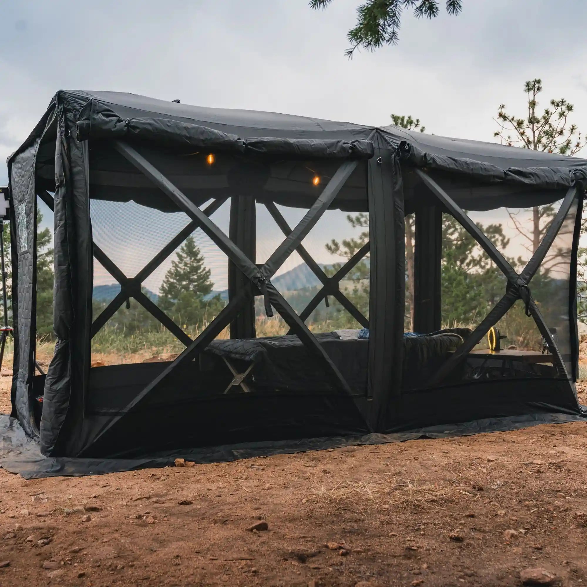 FSR Hub 4 Double pop-up camping tent set up with all windows open in a campsite with trees and mountains visible in the background.