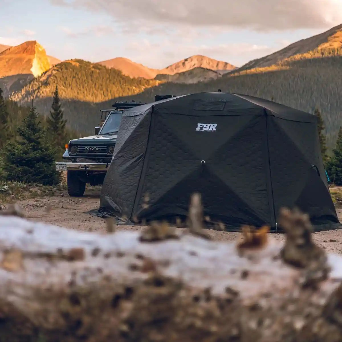 FSR Hub 6 XL pop-up camping tent set up in a mountainous area with a 70 series Toyota Landcruiser parked nearby.